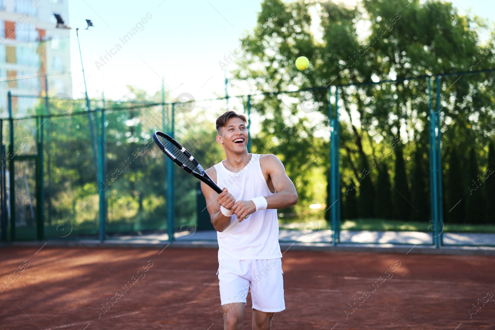 Young man playing tennis at court on sunny day Photo of Young man playing tennis at court on sunny day