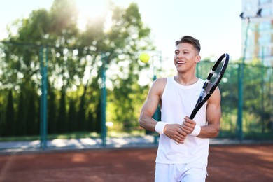 Photo of Young man playing tennis at court on sunny day. Space for text