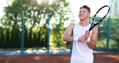 Photo of Young man playing tennis at court on sunny day. Space for text