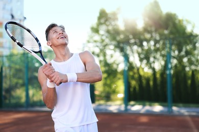 Photo of Young man playing tennis at court on sunny day. Space for text