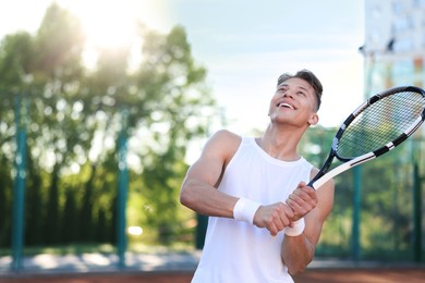 Photo of Young man playing tennis at court on sunny day. Space for text