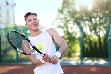 Photo of Young man playing tennis at court on sunny day. Space for text