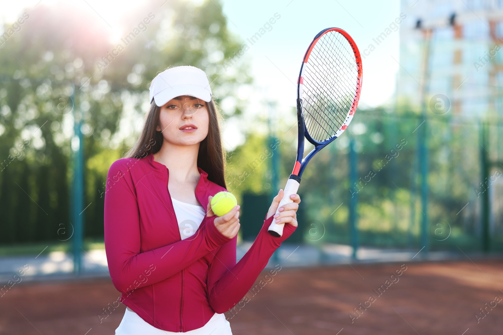 Beautiful woman with racket and ball at tennis court Photo of Beautiful woman with racket and ball at tennis court