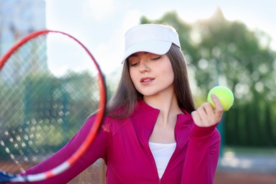 Photo of Beautiful woman with racket and ball at tennis court