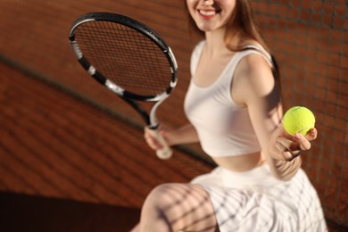 Photo of Beautiful woman with racket and ball at tennis court, closeup