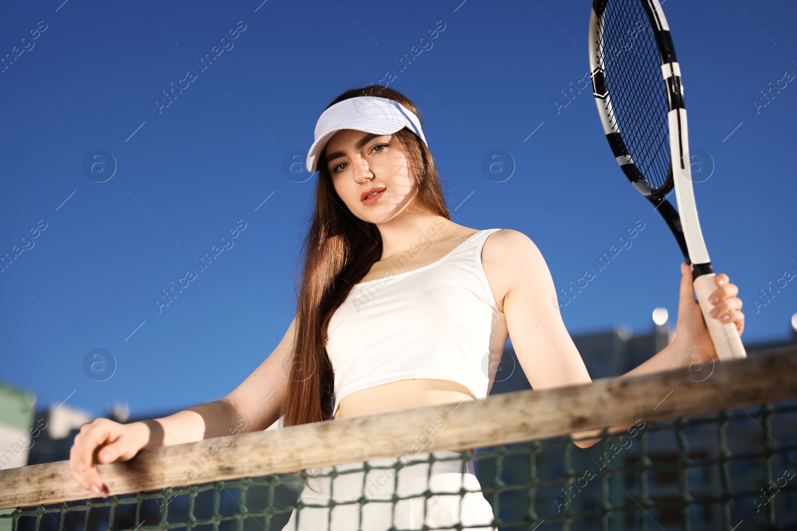 Photo of Beautiful woman with racket at tennis court, low angle view