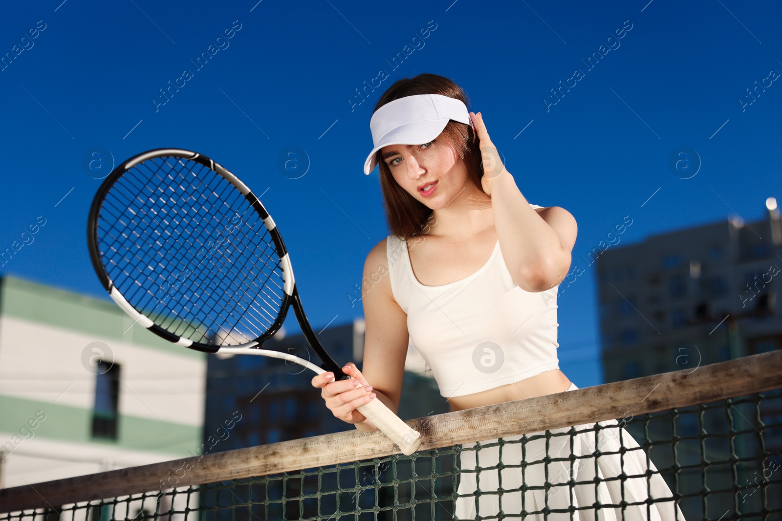 Beautiful woman with racket at tennis court, low angle view Photo of Beautiful woman with racket at tennis court, low angle view