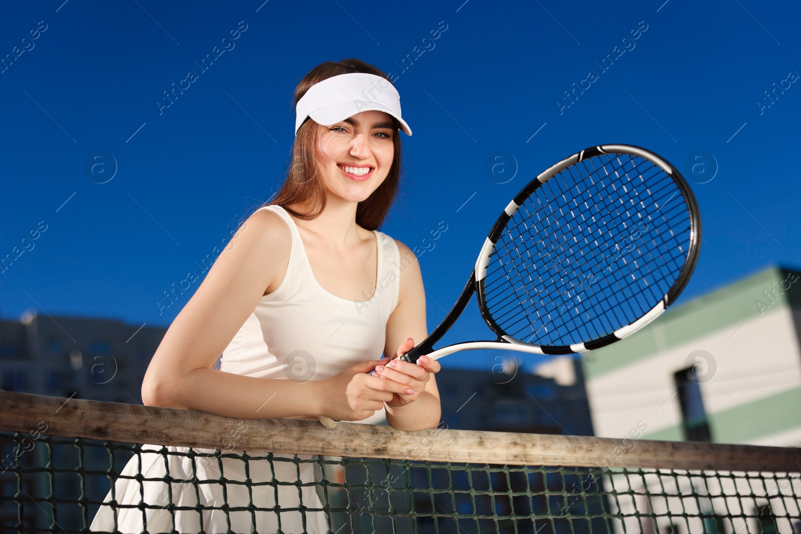 Beautiful woman with racket at tennis court, low angle view Photo of Beautiful woman with racket at tennis court, low angle view
