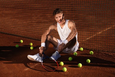 Photo of Happy man with racket and balls at tennis court