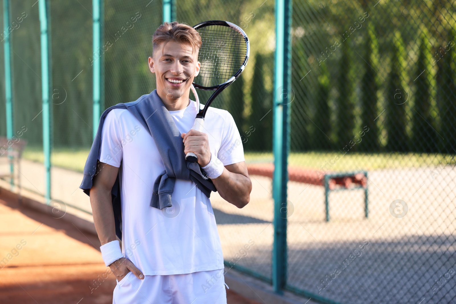 Young man with racket at tennis court. Space for text Photo of Young man with racket at tennis court. Space for text
