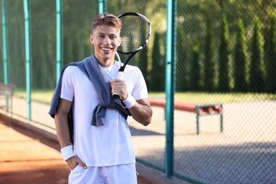 Photo of Young man with racket at tennis court. Space for text