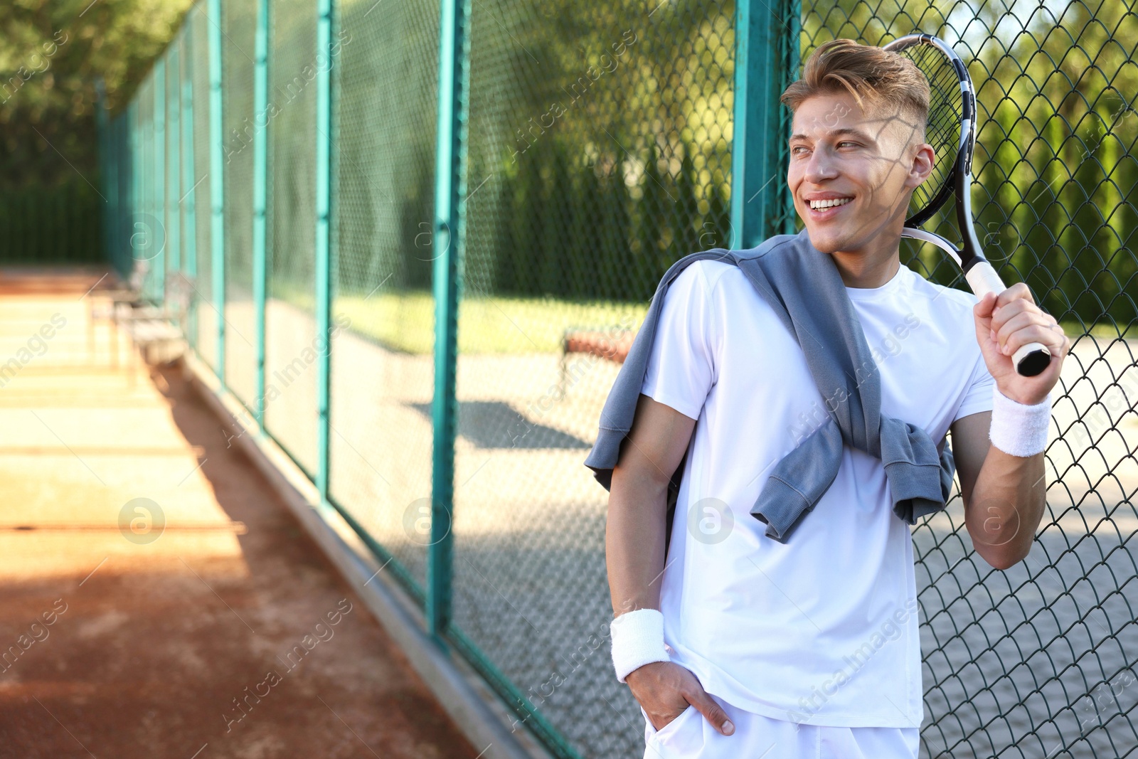 Young man with racket at tennis court. Space for text Photo of Young man with racket at tennis court. Space for text