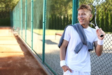 Photo of Young man with racket at tennis court. Space for text