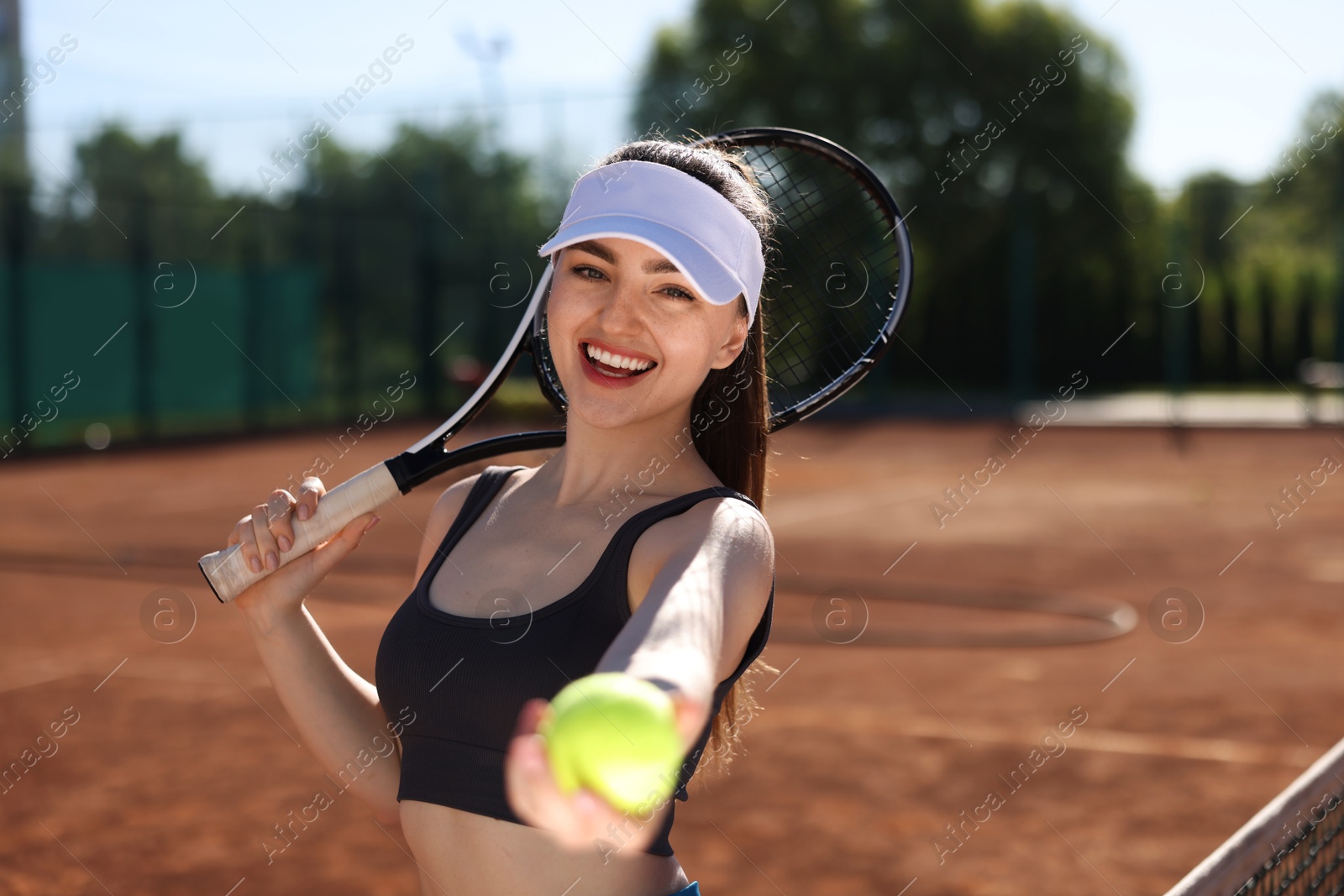 Beautiful young woman with racket and ball at tennis court Photo of Beautiful young woman with racket and ball at tennis court