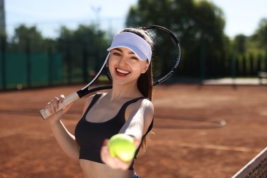 Photo of Beautiful young woman with racket and ball at tennis court
