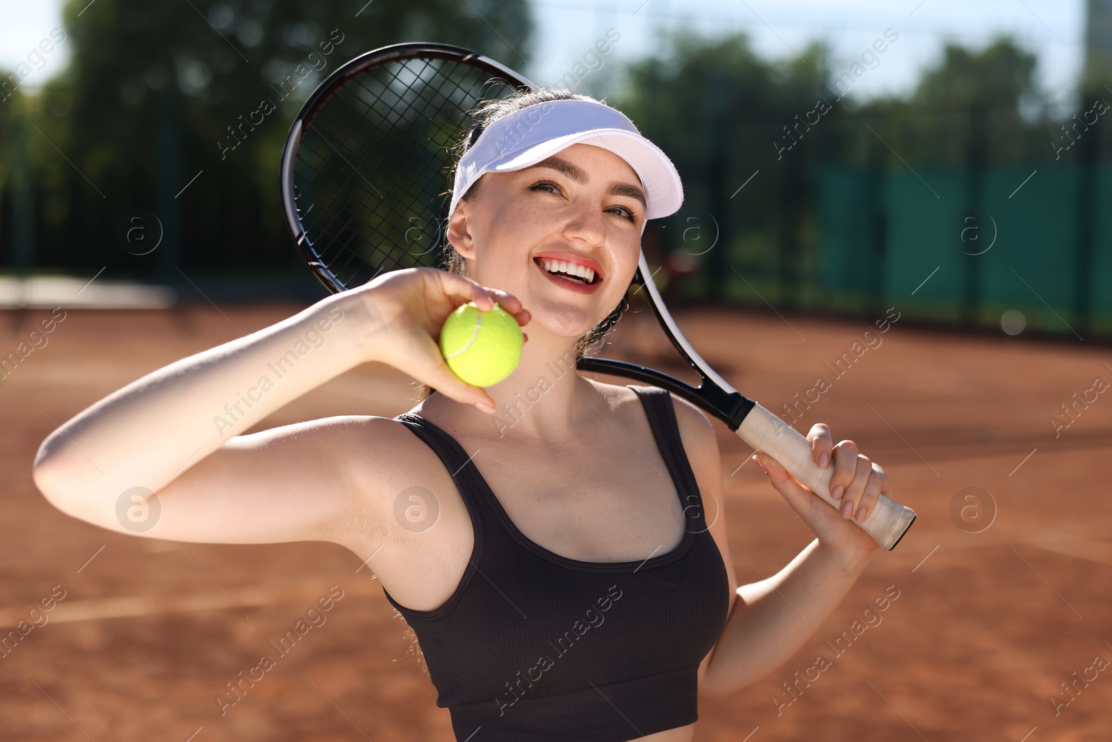 Beautiful young woman with racket and ball at tennis court Photo of Beautiful young woman with racket and ball at tennis court