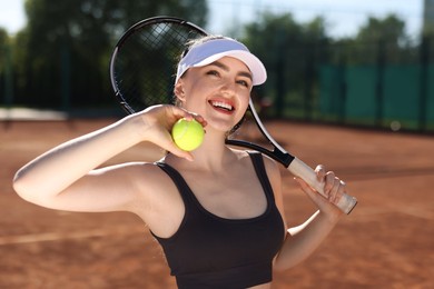 Photo of Beautiful young woman with racket and ball at tennis court