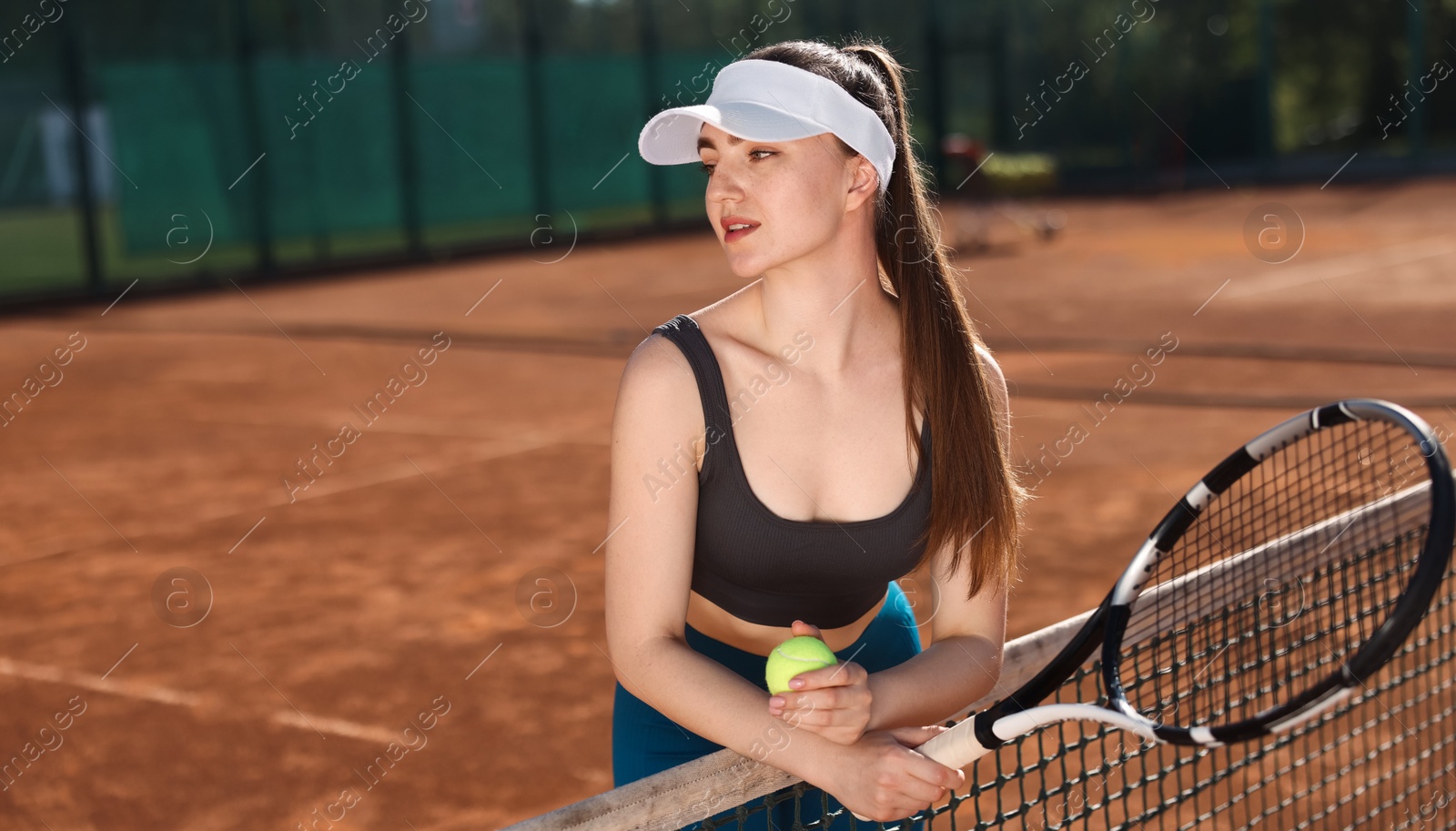 Beautiful young woman with racket and ball at tennis court Photo of Beautiful young woman with racket and ball at tennis court