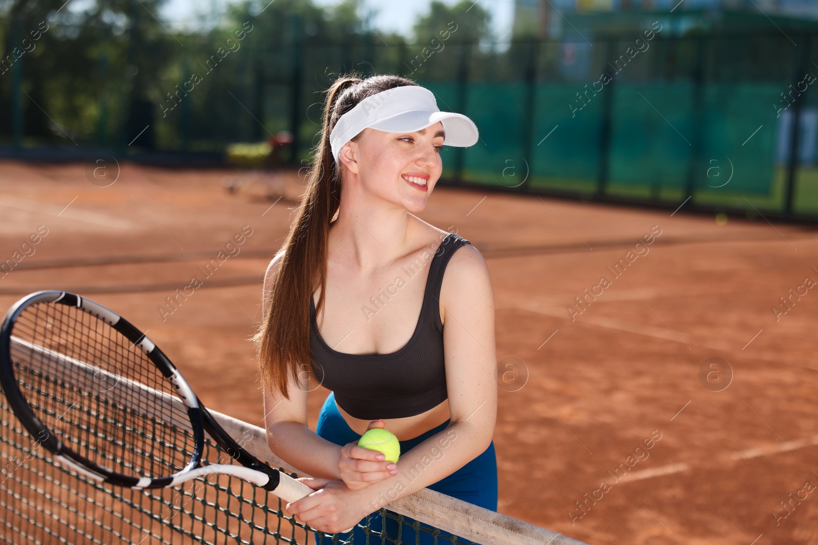 Beautiful young woman with racket and ball at tennis court Photo of Beautiful young woman with racket and ball at tennis court