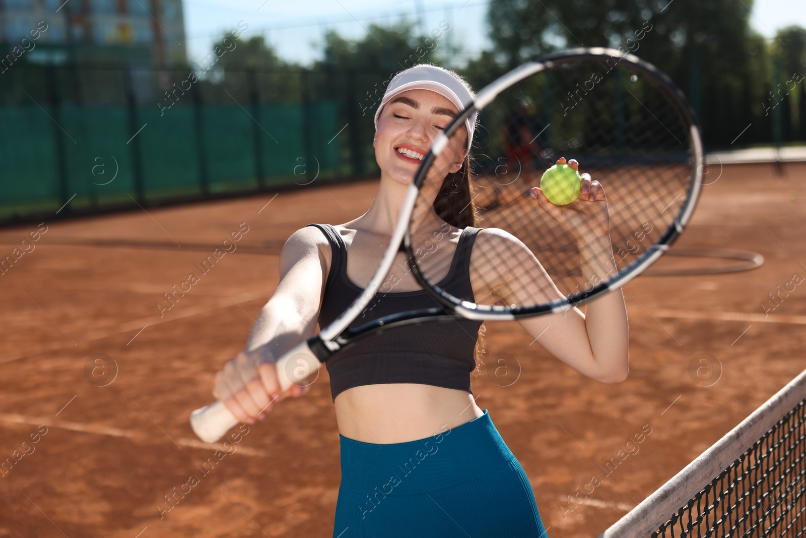 Beautiful young woman with racket and ball at tennis court Photo of Beautiful young woman with racket and ball at tennis court