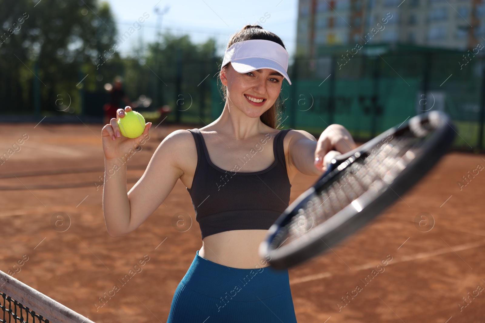 Beautiful young woman with racket and ball at tennis court Photo of Beautiful young woman with racket and ball at tennis court