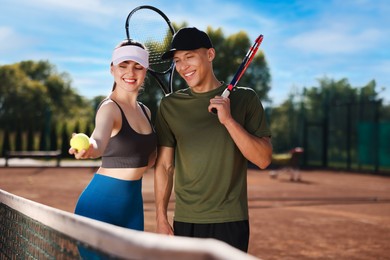 Photo of Happy couple with rackets and ball at tennis court
