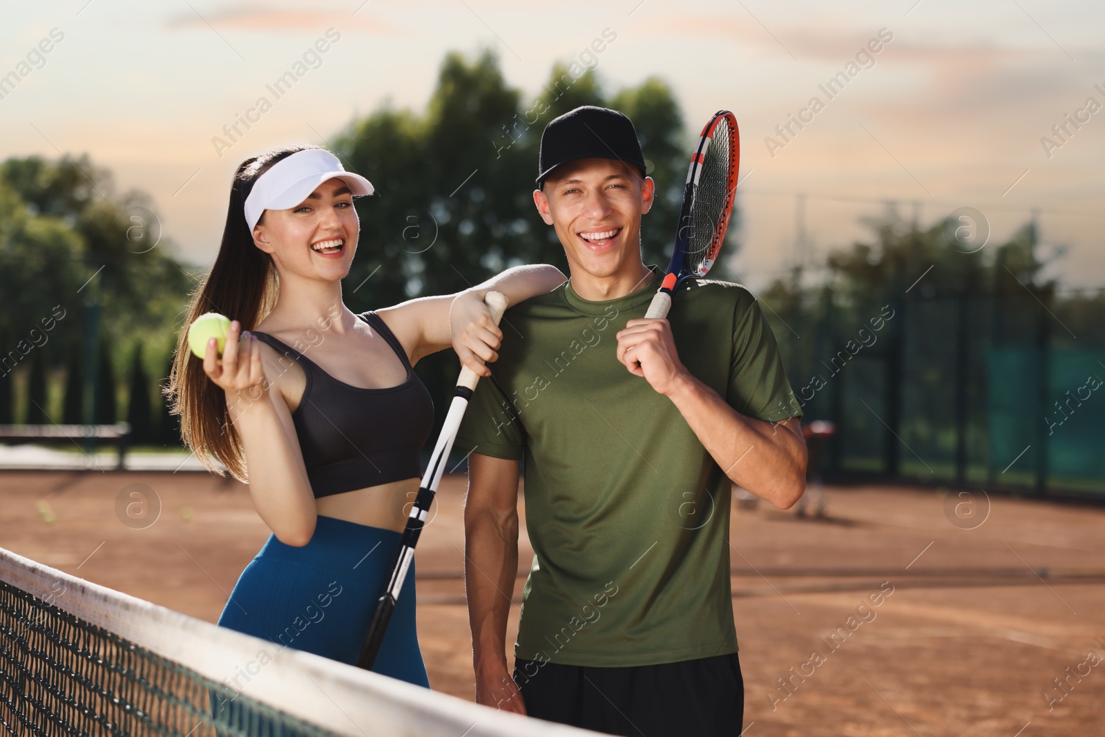 Happy couple with rackets and ball at tennis court Photo of Happy couple with rackets and ball at tennis court