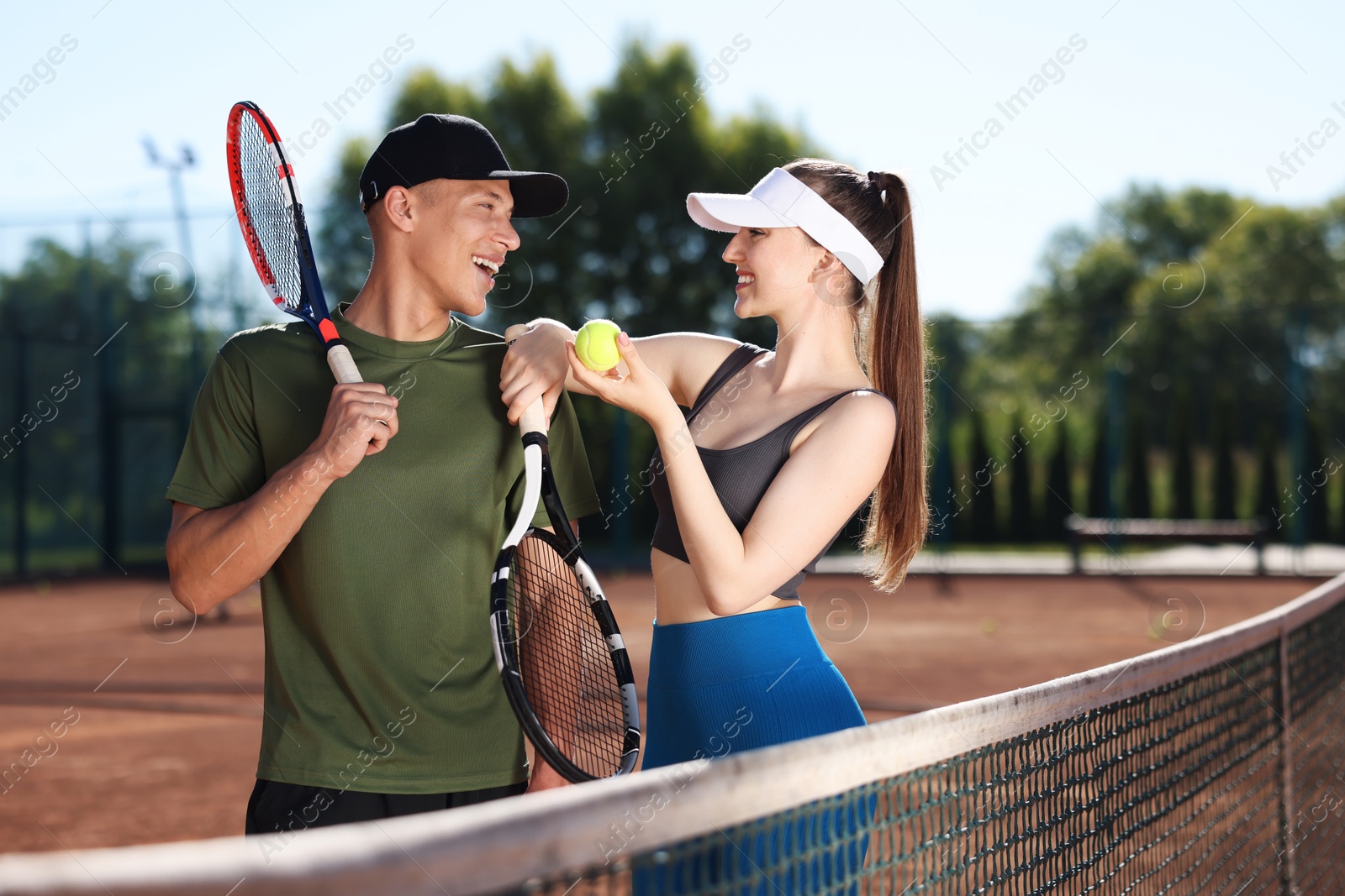Happy couple with rackets and ball at tennis court Photo of Happy couple with rackets and ball at tennis court
