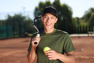 Photo of Smiling young man with racket and ball at tennis court
