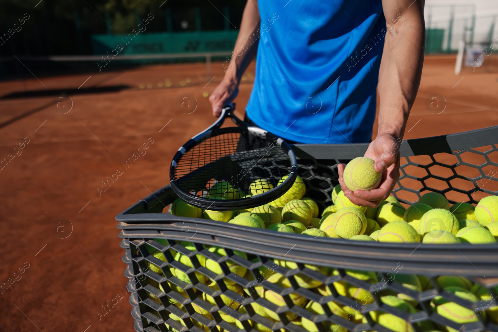 Man taking tennis ball out of cart at court, closeup Photo of Man taking tennis ball out of cart at court, closeup