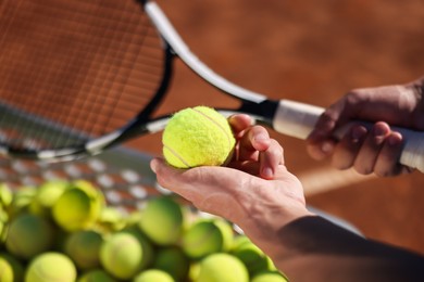 Photo of Man taking tennis ball out of cart at court, closeup