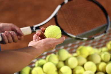 Photo of Man taking tennis ball out of cart at court, closeup