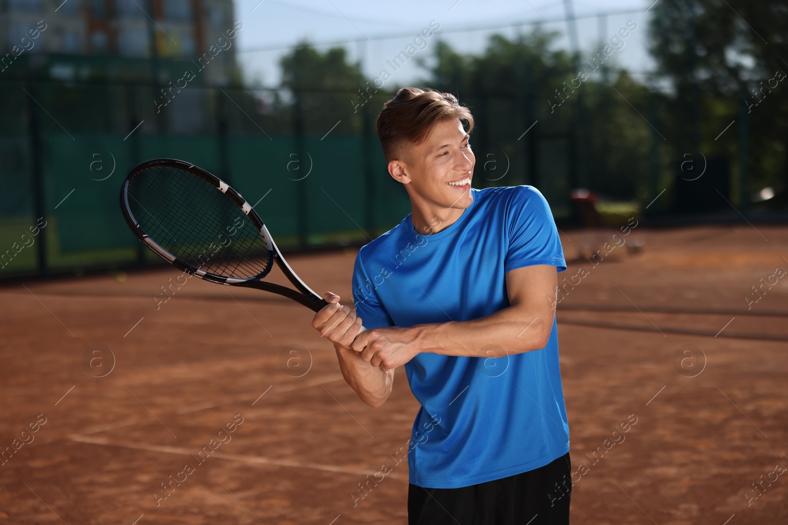 Young man with racket playing tennis at court Photo of Young man with racket playing tennis at court