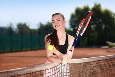 Photo of Happy woman with racket and ball at tennis court