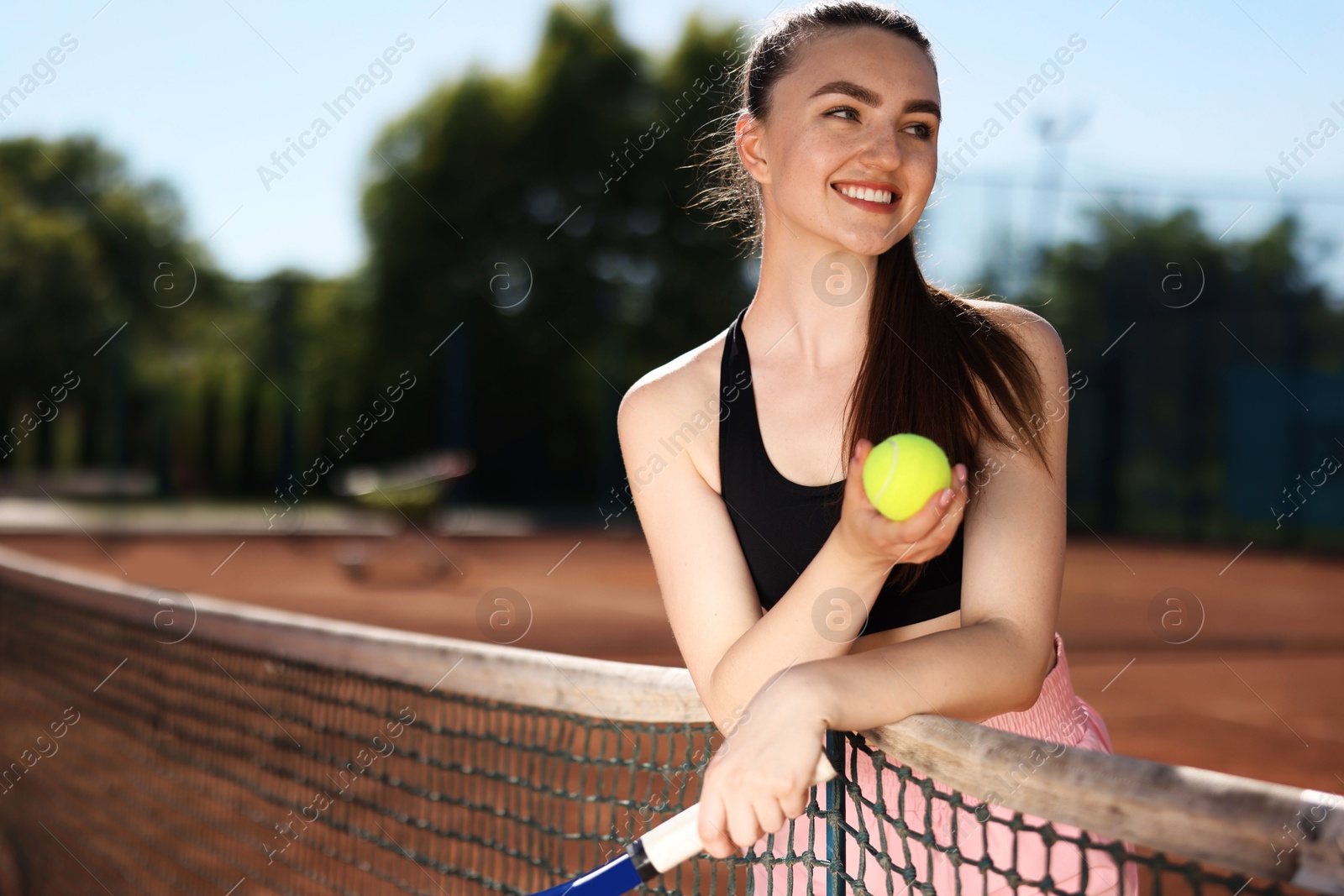 Happy woman with racket and ball at tennis court. Space for text Photo of Happy woman with racket and ball at tennis court. Space for text