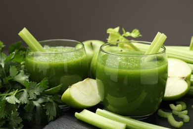 Photo of Superfood. Refreshing smoothie in glasses and ingredients on dark textured table against grey background, closeup