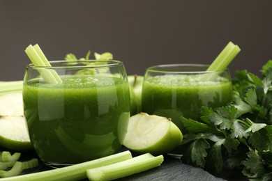 Photo of Superfood. Refreshing smoothie in glasses and ingredients on dark textured table against grey background, closeup