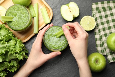 Photo of Superfood. Woman with glass of refreshing smoothie and ingredients at dark textured table, top view