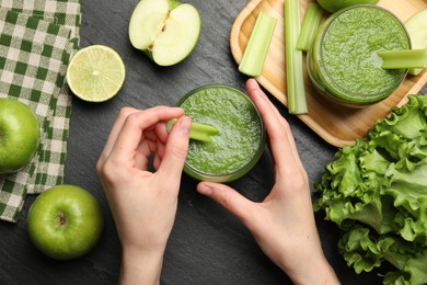 Photo of Superfood. Woman with glass of refreshing smoothie and ingredients at dark textured table, top view