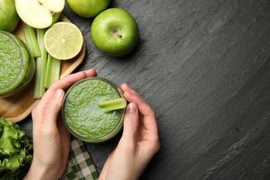 Photo of Superfood. Woman with glass of refreshing smoothie and ingredients at dark textured table, top view. Space for text