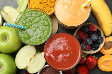 Photo of Superfood. Refreshing smoothies in glasses and ingredients on dark table, flat lay