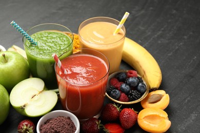 Photo of Superfood. Refreshing smoothies in glasses and ingredients on dark textured table, closeup