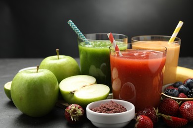 Photo of Superfood. Refreshing smoothies in glasses and ingredients on dark table, closeup