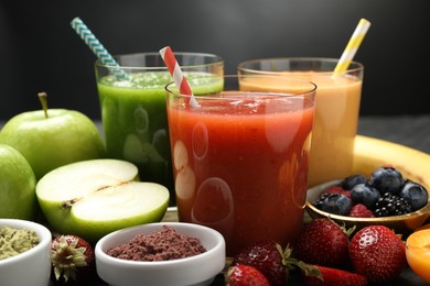 Photo of Superfood. Refreshing smoothies in glasses and ingredients on dark table, closeup