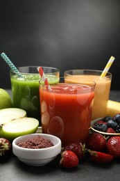 Photo of Superfood. Refreshing smoothies in glasses and ingredients on dark table, closeup