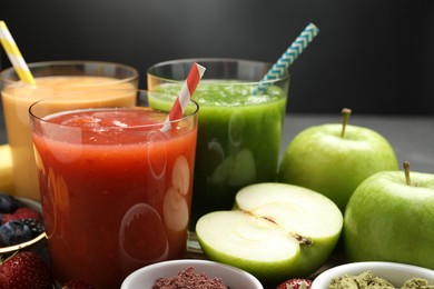 Photo of Superfood. Refreshing smoothies in glasses and ingredients on dark table, closeup