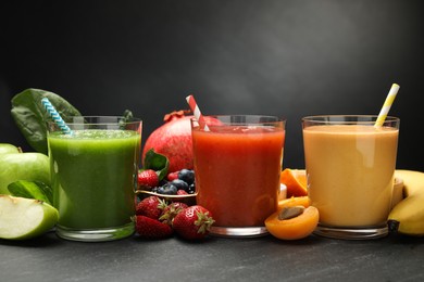 Photo of Superfood. Refreshing smoothies in glasses and ingredients on dark textured table, closeup