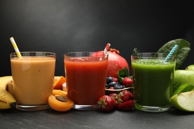 Photo of Superfood. Refreshing smoothies in glasses and ingredients on dark textured table, closeup