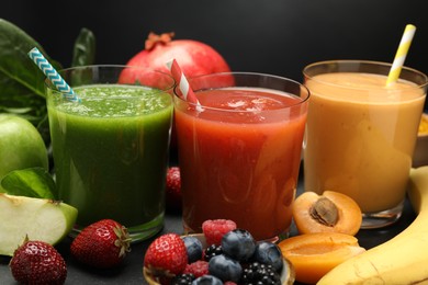 Photo of Superfood. Refreshing smoothies in glasses and ingredients on dark textured table against black background, closeup