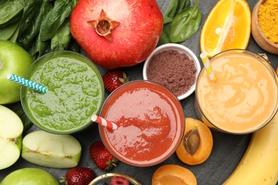 Photo of Superfood. Refreshing smoothies in glasses and ingredients on dark textured table, flat lay